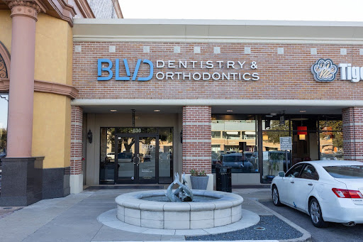 BVD Dentistry and Orthodontics storefront with brick facade, entrance doors, and white car parked outside.