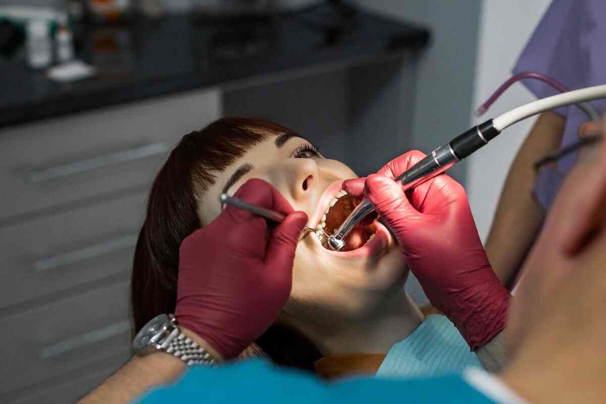 dentist performing dental cleaning Close-up of a dentist using a dental drill and mirror during a patient treatment.