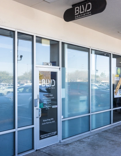 img-blvd-dentistry—orthodontics1 Modern dental office storefront with glass doors and BLVD Dentistry signage, daytime exterior view.