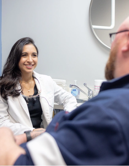 img-blvd-dentistry—orthodontics5 Woman in white coat smiling at man during medical consultation in clinic room.