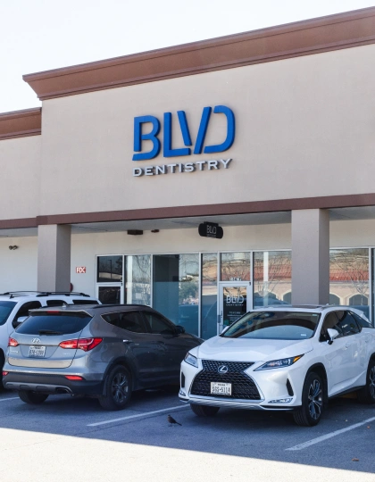 img-blvd-dentistry—orthodontics7 BLVD Dentistry storefront with blue signage and two parked cars in front.