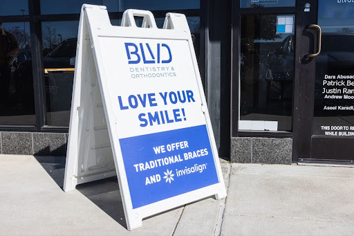 Sidewalk sign for BUD Dentistry advertising braces and Invisalign treatment outside storefront.
