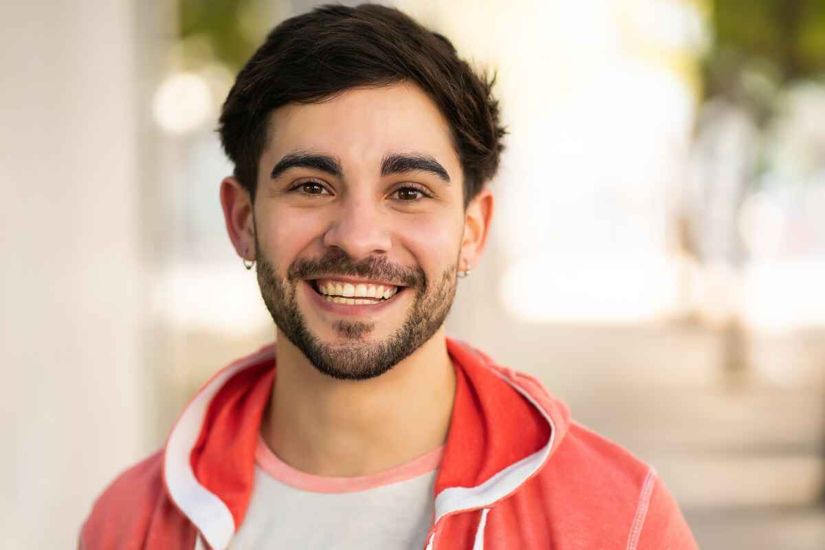 lost tooth long term replacement options Smiling young man showing a healthy, complete smile outdoors